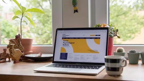 desk with laptop and other items by the window