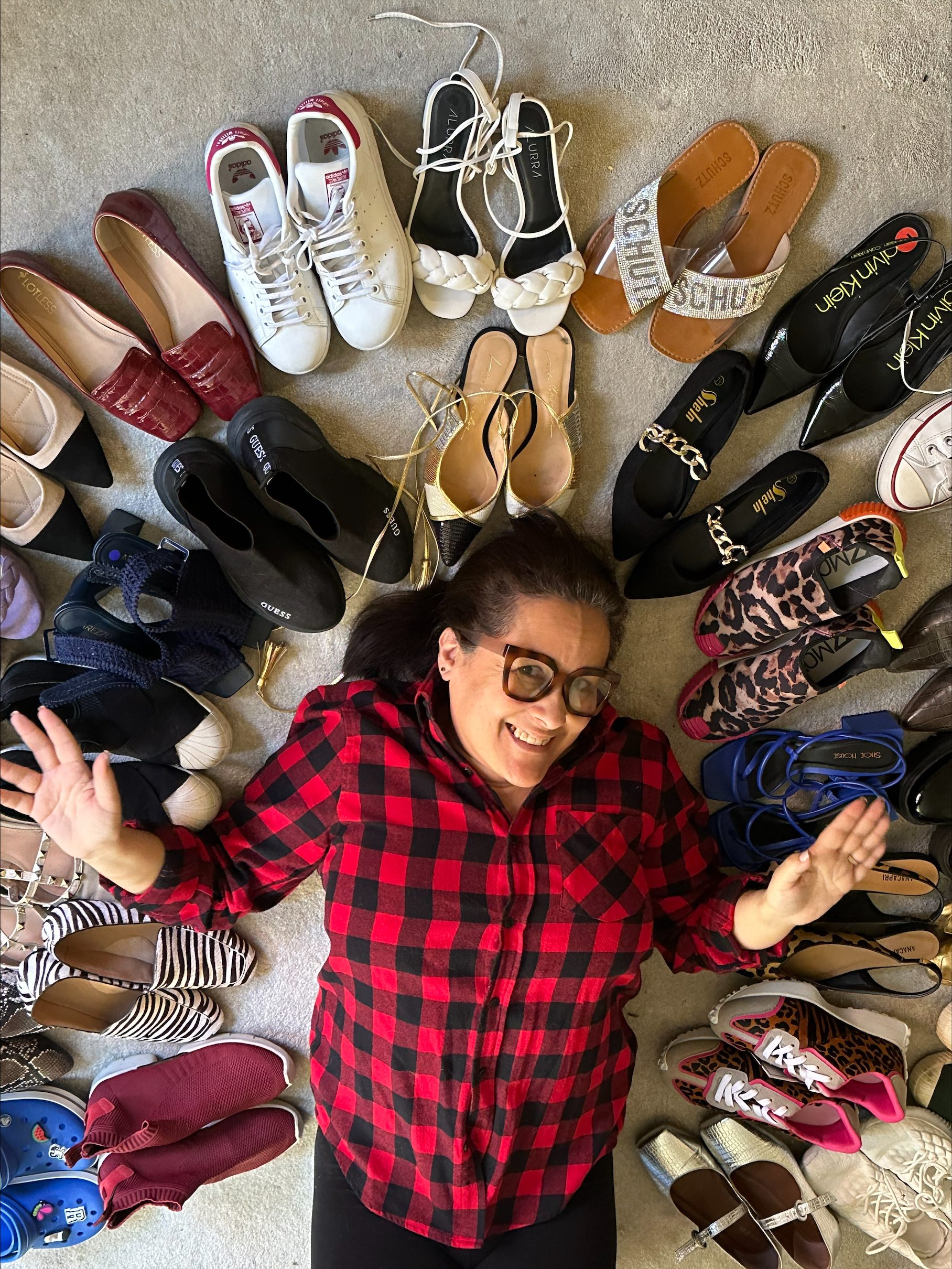 A photo of Renata with many pairs of shoes displayed around her